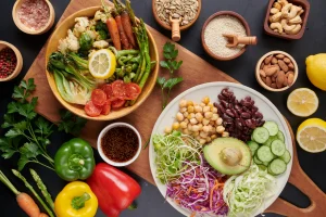 A salad bowl, a plate full of healthy vegetables, healthy fats, nuts, seeds and grains on a wooden tray
