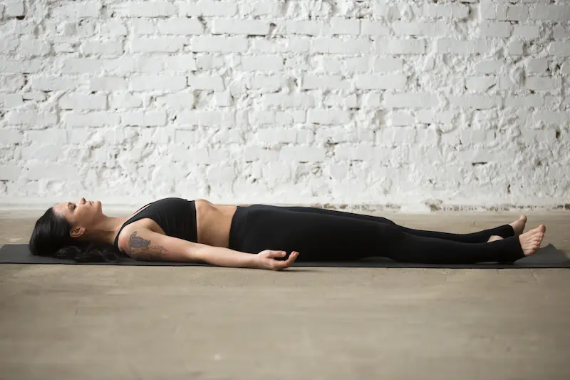 young-yogi-attractive-woman-savasana-pose-white-loft-background_Activ Living Community