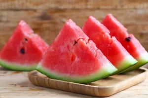 Slices of watermelon with black seeds on a wooden tray